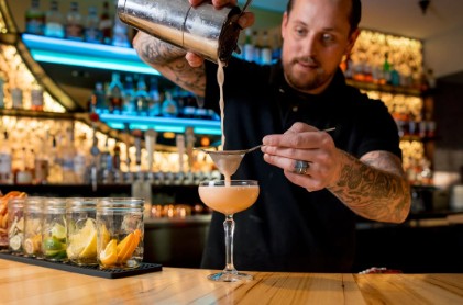 A bartender straining a drink before serving it at Cafe Vino.
