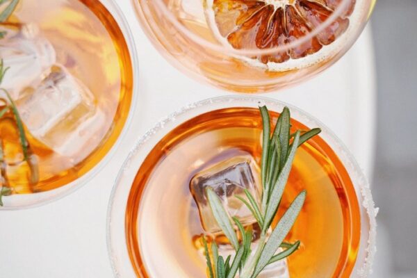 Three orangish drinks with an orange peel and green garnish created at Herbal Mocktails.